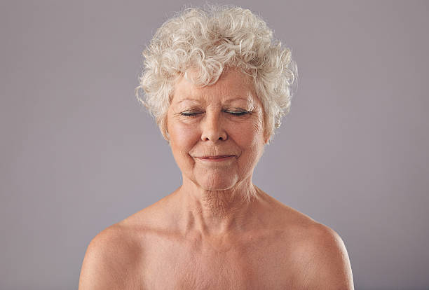 Relaxed old woman in thought Close-up of relaxed old woman on grey background with her eyes closed in thought. Naked senior female against grey background. older woman eyes closed stock pictures, royalty-free photos & images