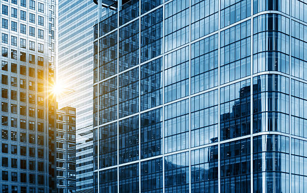 посмотреть на современные стеклянные небоскребы отражая небесно-голубой - financial building стоковые фото и изображения