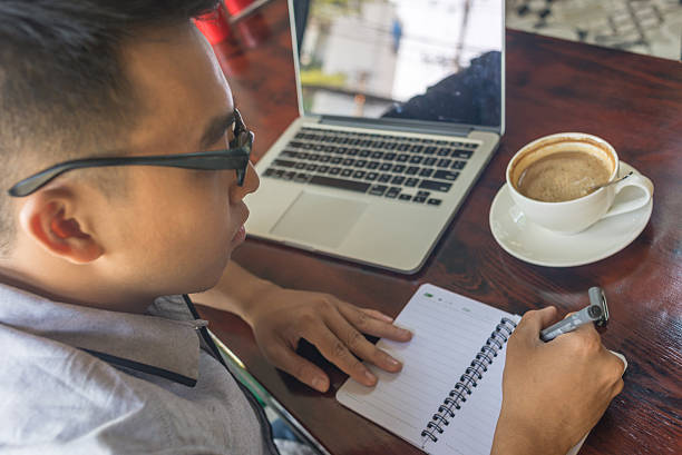 istock Young Asian student writing notes on the wooden table 507756482