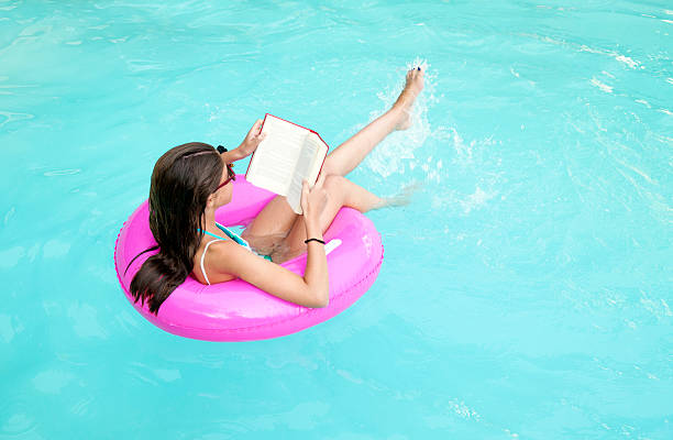 Child reading while floating on a pink lifesaver
