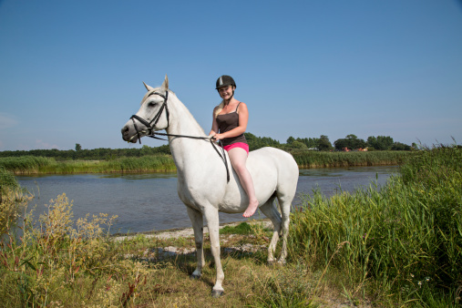 Young woman Sitting on a white Horse with no saddel