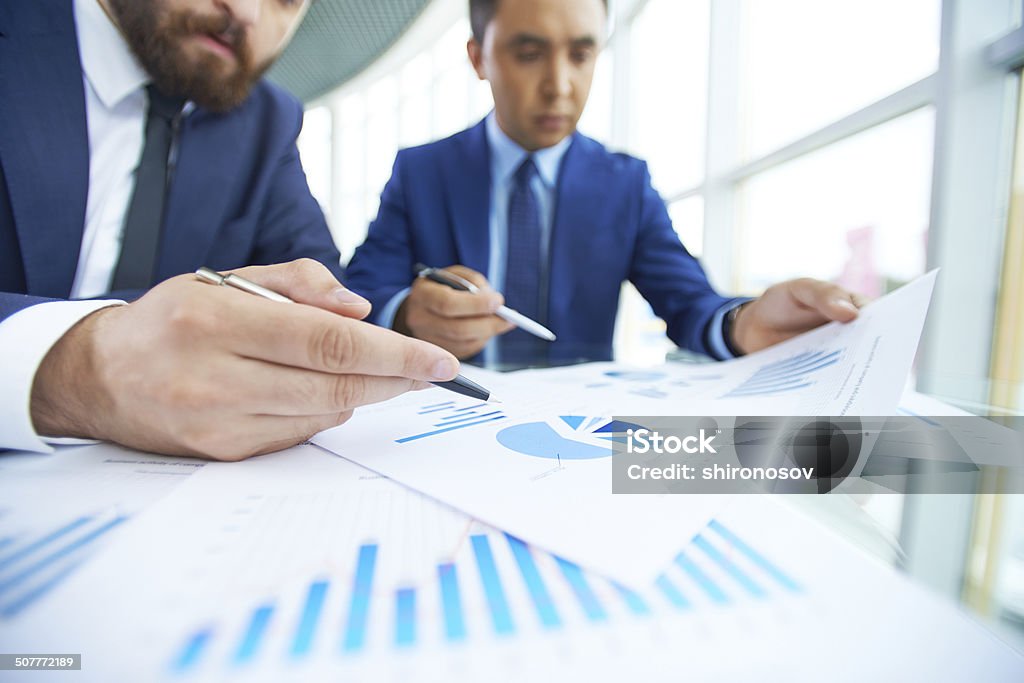 Paperwork Image of businessman pointing at paper during discussion with his partner at meeting Adult Stock Photo