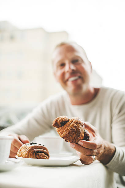 Man in a cafe having a coffee break with croissants