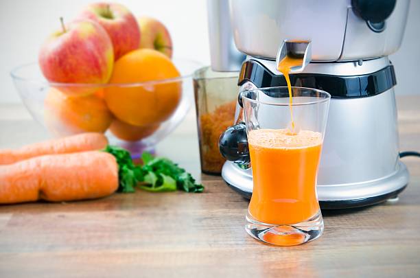 juicer and carrot juice. fruits in background - 榨汁機 個照片及圖片檔