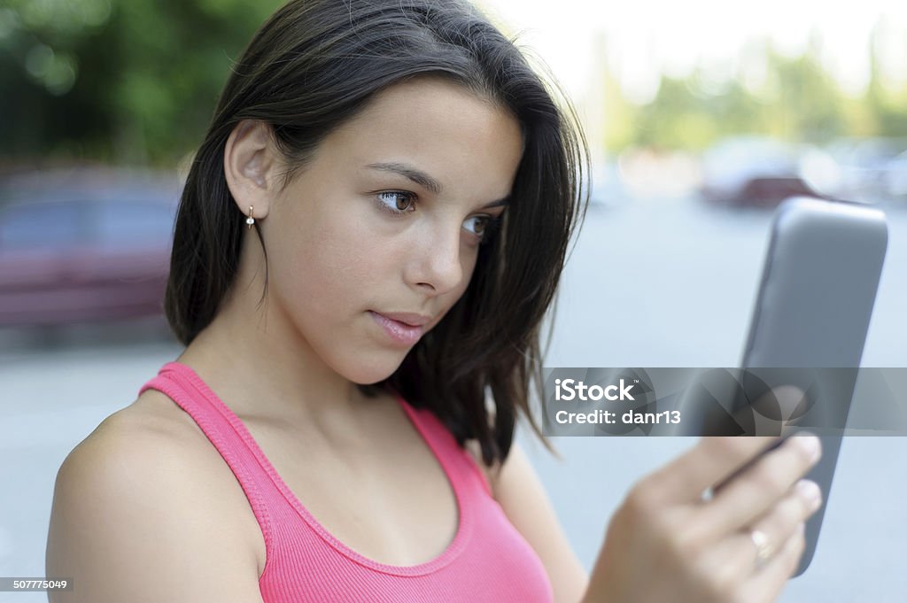 Girl using tablet PC outdoor Young brunette using touchpad outdoor. Focus on the girl Adult Stock Photo