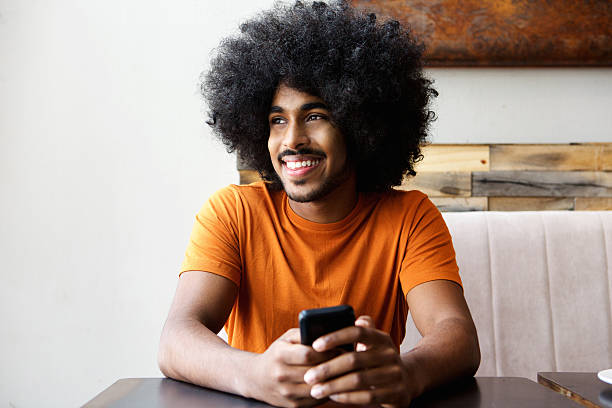 istock Smiling african american man sitting at table with mobile phone 507789174