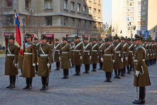 Santiago, Сhile - July 25, 2014: Members of the Carabineros marching with a ceremonial flag as part of the changing of the guard ceremony at La Moneda in Santiago, Chile. La Moneda is the Presidential Palace in the centre of Santiago.