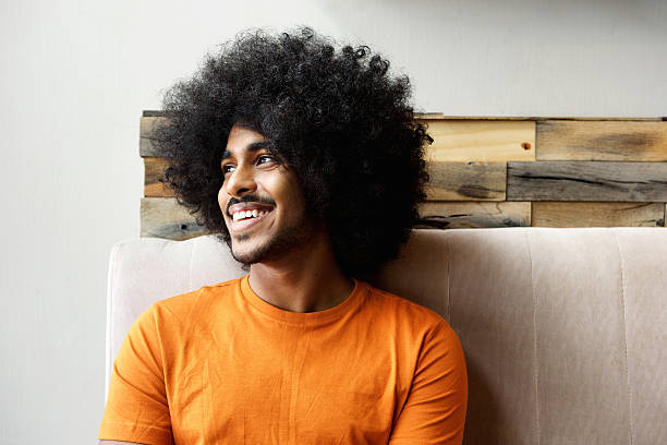 Smiling young black man with afro looking away Close up portrait of a smiling young black man with afro looking away afro man stock pictures, royalty-free photos & images