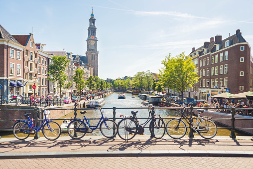 A view over one of the many canals in Amsterdam. Bicycles, canals, boats and the Westerkerk in the back, making this photo completely and typical Amsterdam.