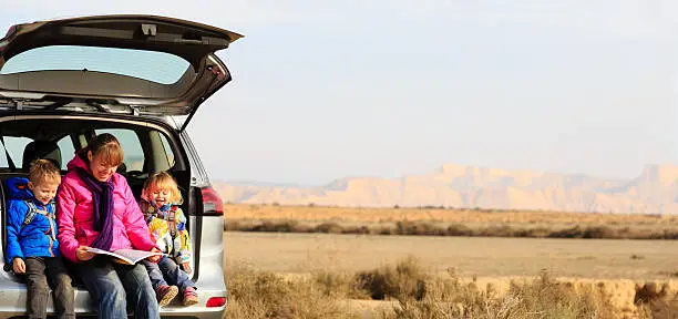 Photo of mother with kids looking at map while travel by car