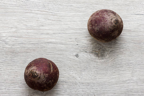 Two whole red beetroots on wooden textured table