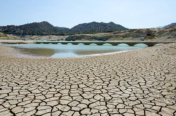 Dry river with cracks leading to water basin Villajoyosa, Spain 12. July 2015. Amadorio Reservoir. Water basin. Drought.  drought stock pictures, royalty-free photos & images