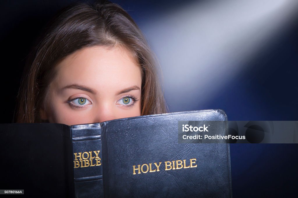 Portrait of teenage girl reading bible Portrait of teenage girl with beautiful eyes reading bible. Close Adult Stock Photo