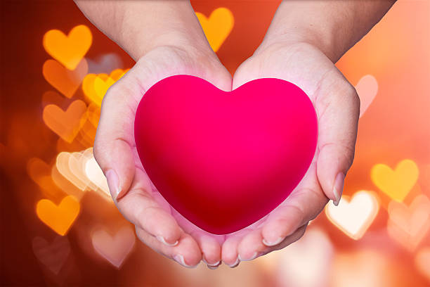 istock Pink Heart in hands on nature background 507802614
