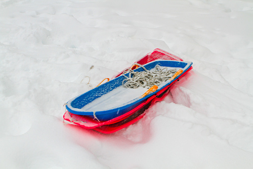 A pile of plastic sleds or toboggans piled on snow created by the blizzard of 2016