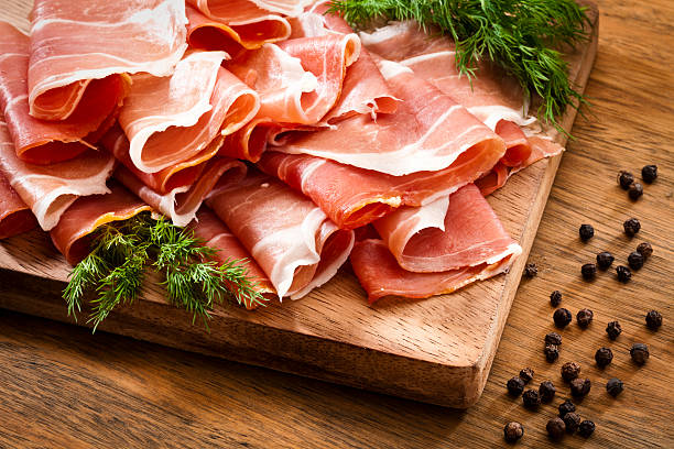 rebanadas de jamón serrano en mesa de madera rústica - prosciutto fotografías e imágenes de stock