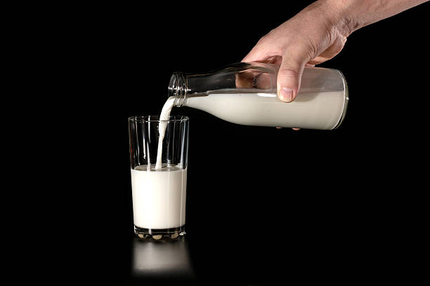 istock man pours cow's milk from glass bottles in a glass 507804892