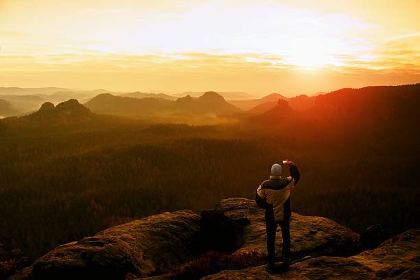 istock Man with phone. Dreamy landscape, orange mist in beautiful valley 507805032