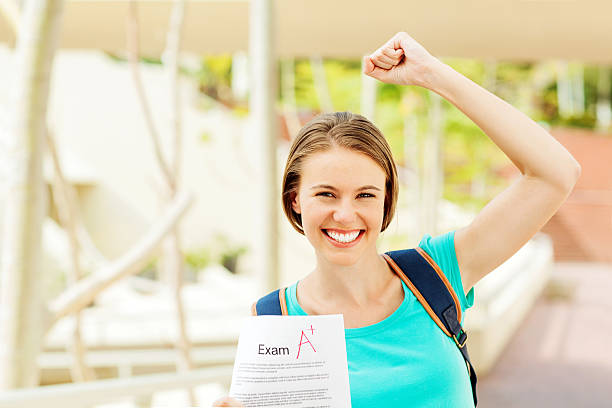 istock Student Clenching Fist While Showing Exam Paper With A+ Grade 507823077