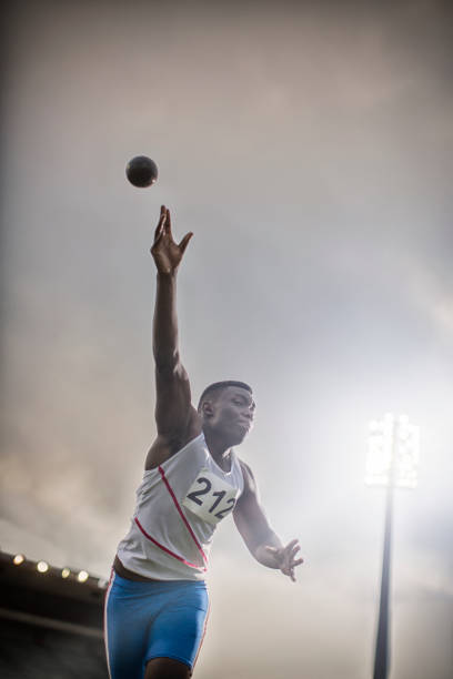Male holding a shot put before throwing it.