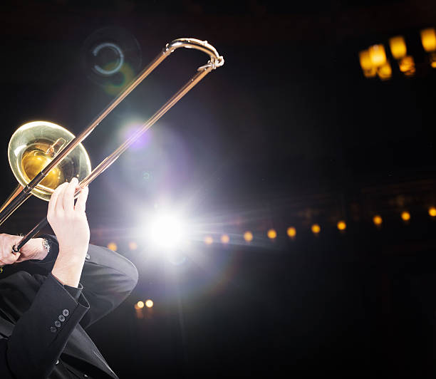 posaune-spieler mit hintergrundbeleuchtung - performance big band trombone trumpet stock-fotos und bilder