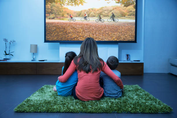 mère et enfants regardant la télévision dans le salon - man made structure high definition television domestic room living room photos et images de collection