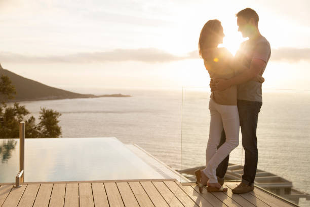 pareja en una terraza de madera con vistas al océano - face to face twilight togetherness vertical fotografías e imágenes de stock