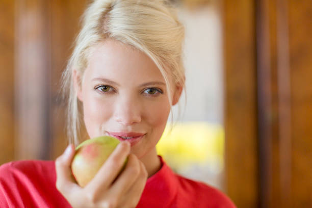 Young woman with red apple on top of head
