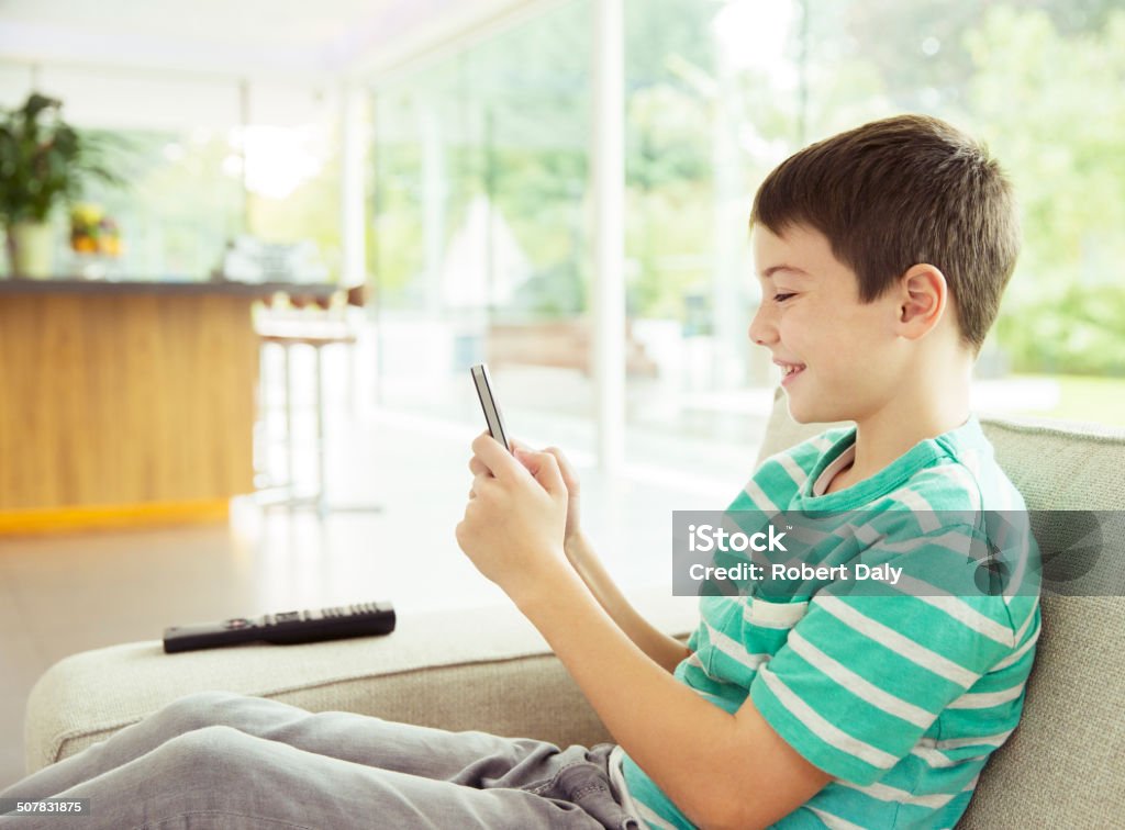 Boy using cell phone on sofa  Living Room Stock Photo