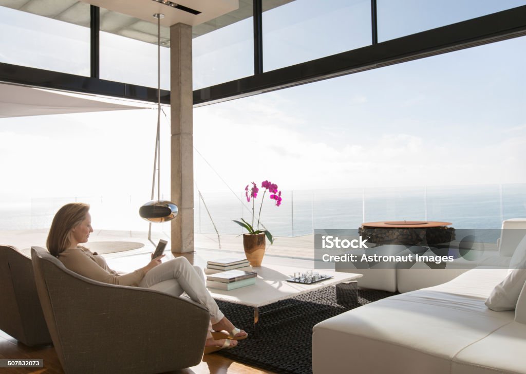 Woman using cell phone in modern living room  Luxury Stock Photo