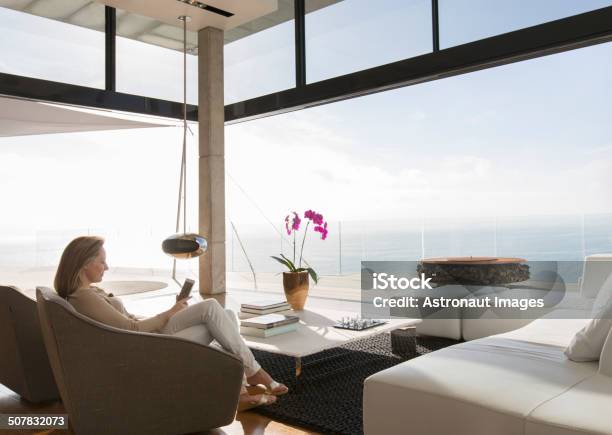 Woman Using Cell Phone In Modern Living Room Stock Photo - Download Image Now - Luxury, Home Interior, Domestic Life