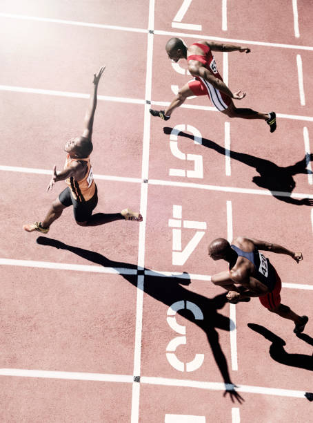 бегуны, пересекающие финишную черту - mens track фотографии стоковые фото и изображения