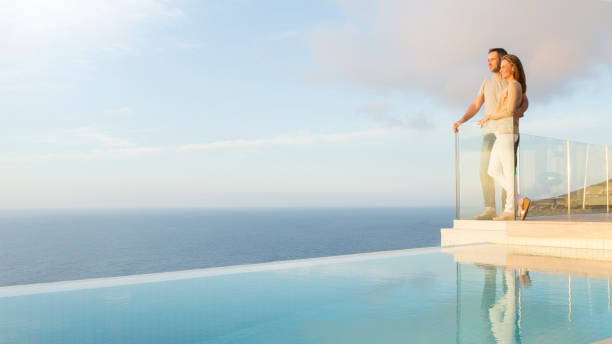 coppia con vista sull'oceano dal balcone moderno - infinity pool foto e immagini stock