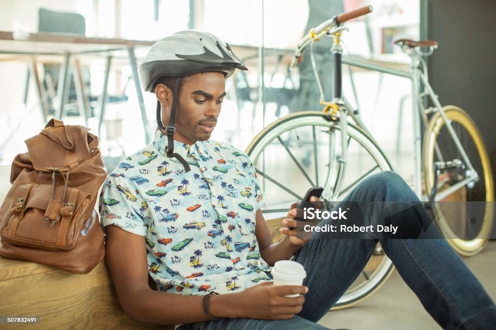 Man in bicycle helmet using cell phone in office  Bicycle Stock Photo