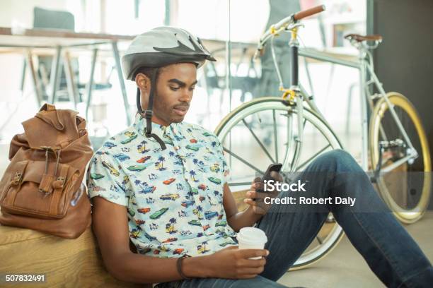 Man In Bicycle Helmet Using Cell Phone In Office Stock Photo - Download Image Now - Bicycle, Latin American and Hispanic Ethnicity, Smart Phone