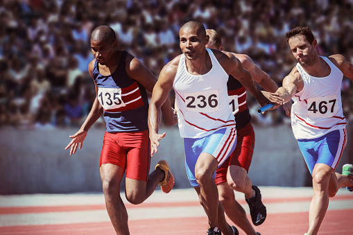 Three senior Caucasian athletes in blue gear jogging on a red athletic track