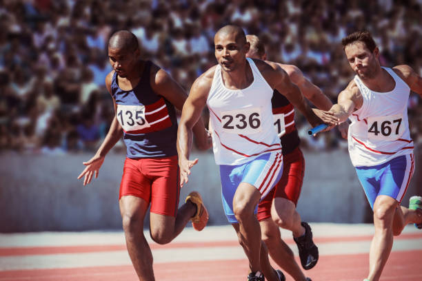 Relay runners exchanging batons on track  relay stock pictures, royalty-free photos & images