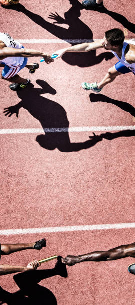 istock Relay runners handing off baton on track 507832815