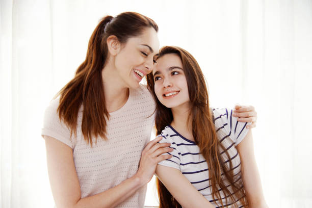 Happy Bolivian woman with her teenager daughter embracing each other and smiling. White background.