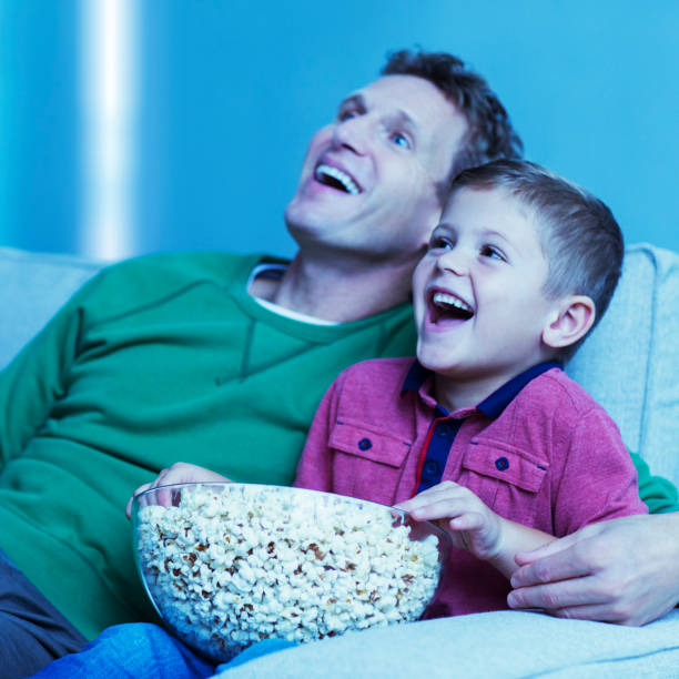 pai e filho assistindo televisão no sofá - entertainment center watching tv television popcorn - fotografias e filmes do acervo