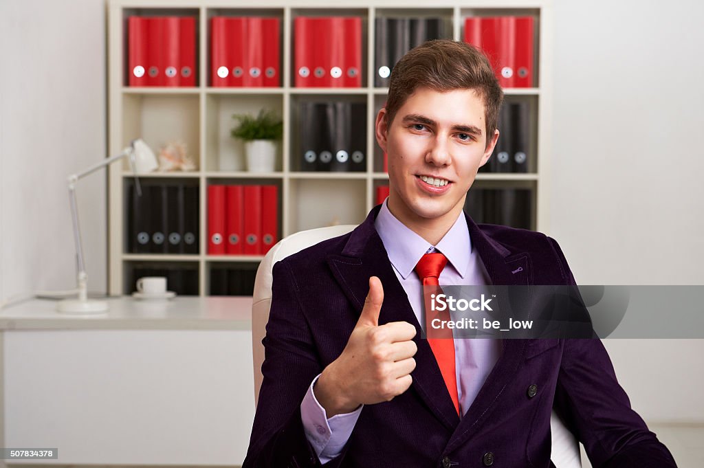 Businessman giving thumbs up Portrait of young businessman giving thumbs up 2015 Stock Photo