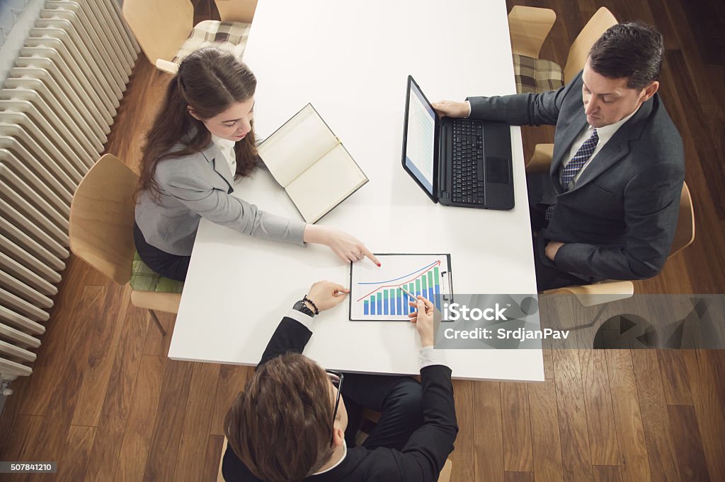 Analyzing Financial Stats Group of financial experts analyzing financial statistics, having a conversation at the office and making suggestions on improving their business project. Improvement Stock Photo