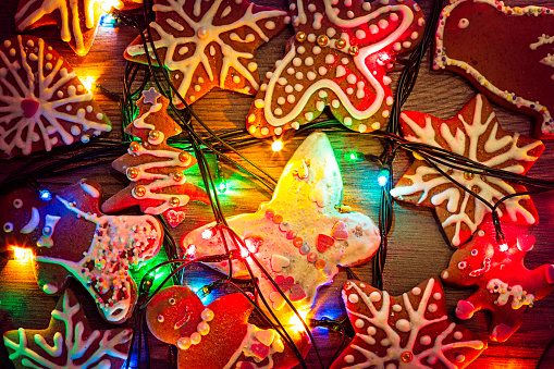 The gingerbread cookies and christmas lights on plank wood table