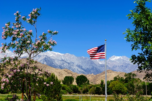 An American flag with Sierra Nevada mountain range in California in the background.