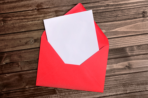 Red envelope with empty paper on wooden table