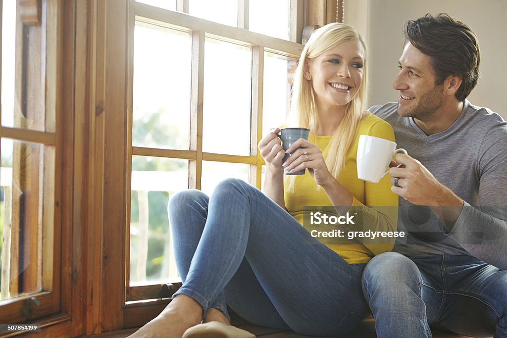 You're the cream in my coffee Shot of a happy couple enjoying a hot drink together next to a window at home 30-39 Years Stock Photo