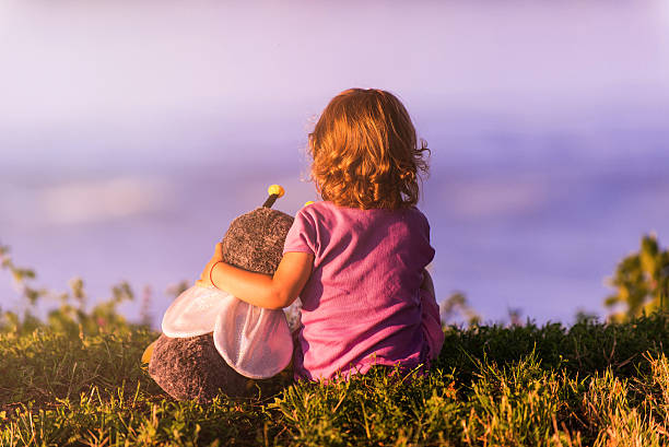 Little girl on riverbank holding her frind