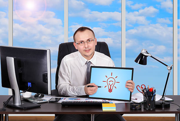 businessman sitting in office and holding tablet with lamp