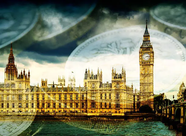 Famous London Tourist attraction Big Ben and the Houses of Parliament in England, with stacks of English Pound coins. Concept image suggesting money and government finances.
