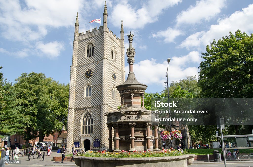 Reading Minster and Queen Victoria Monument Reading, UK - September 10, 2015: Pedestrians walking in the sunshine past the historic Reading Minster church, also known as Saint Mary the Virgin with the Queen Victoria Jubilee Fountain in the foreground.  Sunny afternoon in September. 1 O'Clock Stock Photo